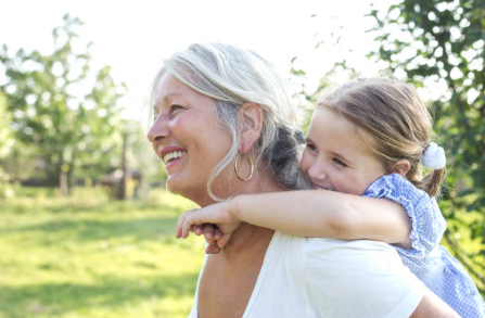 A woman giving her grand daughter a piggyback ride and smiling after signing up for a debt management program