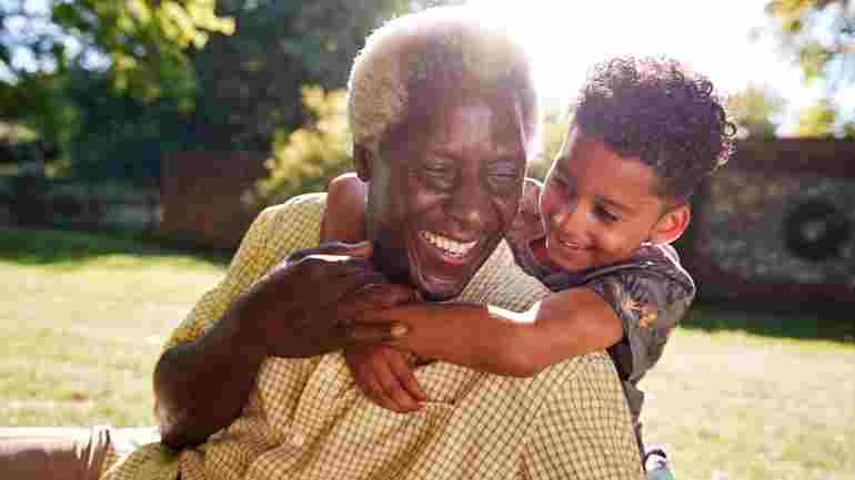 An elderly man giving his grandson a hug and smiling after signing up for a debt management plan
