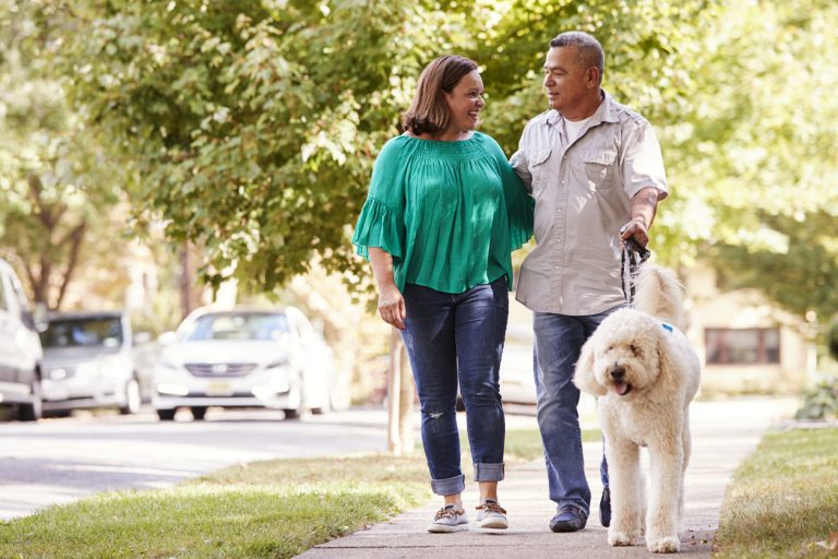 Senior Couple Walking Dog Along Suburban Street after receiving first time home buyer counseling