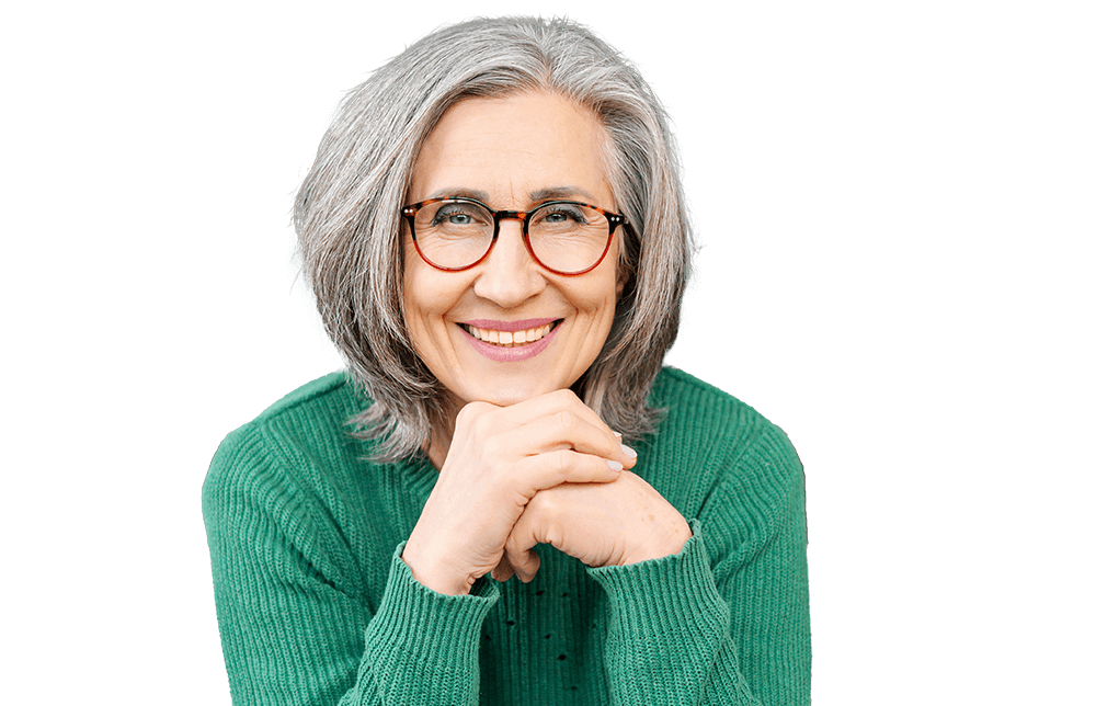 A woman with gray hair and glasses smiles, with her hands clasped.